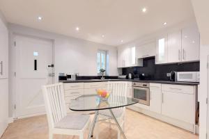 布伦特里Panfield House的厨房配有玻璃桌和白色橱柜