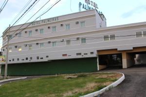 卡希亚斯公爵城Hotel Palmeiras Ltda的一座白色的大建筑,设有绿色的墙壁