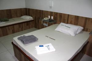 卡希亚斯公爵城Hotel Palmeiras Ltda的客房设有一张带电话和毛巾的床。