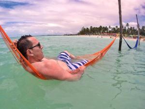 马拉戈日Praia Hostel的躺在水中的吊床上的人
