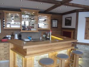 斯拉德明加尼兰德豪斯特勒肯巴赫酒店的厨房设有带凳子的大型木制酒吧