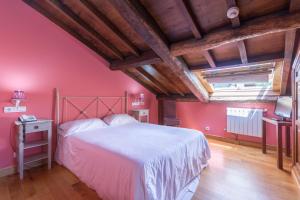 圣地亚哥－德孔波斯特拉Asador de Roxos Casa Albardonedo的卧室设有粉红色的墙壁和一张大床