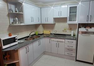 萨拉曼卡Apartamento Norte Comfort的厨房配有白色橱柜、水槽和微波炉