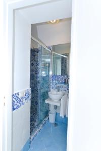 卡普里La Perla Blu的浴室铺有蓝色和白色瓷砖,配有水槽