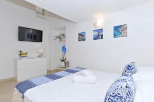 卡普里La Perla Blu的一间白色卧室,配有床和电视