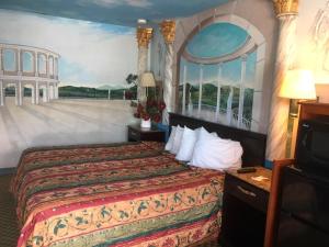加洛韦Deluxe Inn的酒店客房设有一张床,墙上挂有绘画作品