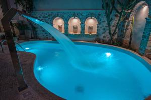 罗希姆诺Thalassa Boutique Hotel的蓝色灯光的客房内的按摩浴缸