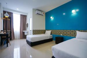 乔治市Grand FC Hotel的酒店客房设有两张床和蓝色的墙壁。