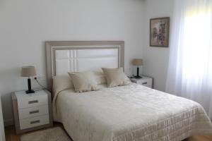 埃利松多Apartamento Datue的一间卧室配有一张白色床、两个床头柜和两盏灯。