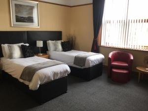利物浦Woodlands Guest House的酒店客房,设有两张床和一张红色椅子