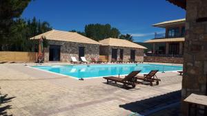 艾迪普索斯Almyra Holiday Village的一个带椅子的游泳池以及一座房子