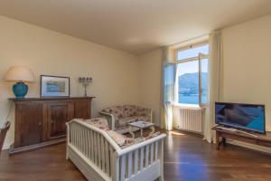 格里安泰卡德纳比亚Apartment Anna - Griante的一间设有婴儿床、电视和椅子的房间