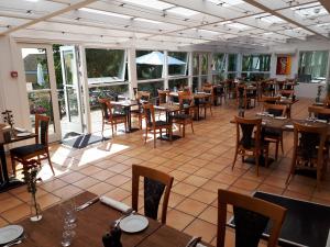 斯泰厄Møn Golf Resort - Hotel Præstekilde的餐厅设有木桌、椅子和窗户。