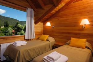 圣马丁德洛斯Del Sauco Apart & Spa的小木屋内的两张床,设有窗户