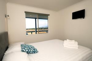 雅纳基普罗姆盖特逍遥度假屋的白色的卧室设有床和窗户