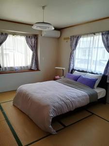 仙台Jukichi Owada Residence的一间卧室设有一张大床和两个窗户。