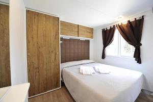 佩斯基耶拉德加达意大利贝拉露营酒店的卧室配有白色的床和木门