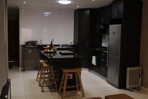 德班维尔DCS Accommodation Cape Gate的厨房配有黑白电器和带凳子的台面
