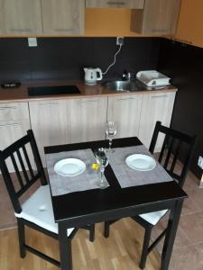 波兹南Midi的一张带两把椅子的黑桌和一张带两个盘子的桌子