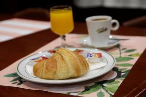 塞维利亚Basic Hotel Puerta de Sevilla的一盘羊角面包和一杯咖啡及一杯果汁