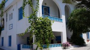 纳克索乔拉Hotel Hara的白色的建筑,有蓝色的窗户和树
