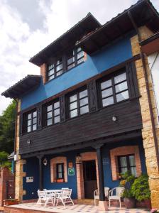 因菲耶斯托Casas Rurales Asturias Campon Antrialgo的前面有白色桌子的蓝色建筑
