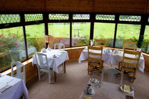 卡林福德莫恩维尔食宿酒店的餐厅设有白色的桌椅和窗户。