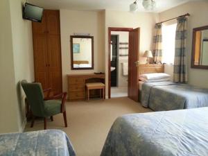 基拉尼麦克劳斯骑马场农家乐的一间卧室配有两张床、一张桌子和一面镜子