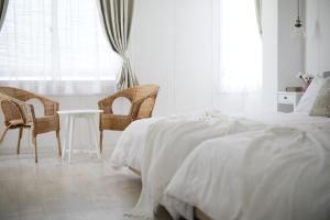 大阪Bijou Suites Sorriso的一间卧室配有一张床、两把椅子和一张桌子