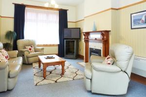 因弗卡吉尔阿德莫诺康特汽车旅馆&公寓的客厅配有椅子、电视和桌子