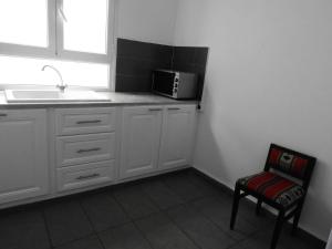 哈马马特Appartement quartier Dar Sebastian, Hammamet的厨房配有白色橱柜、微波炉和椅子