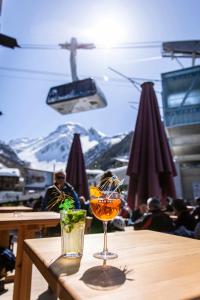 格里门茨Hôtel Alpina - Swiss Ski & Bike Lodge Grimentz的一张木桌,桌子上放着两杯饮料,山地