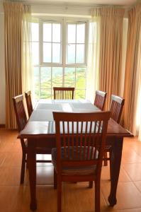 努沃勒埃利耶Villa Spring Acre的餐桌、椅子和大窗户