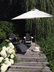 埃曼B&B De Koraal的庭院配有两把椅子和一把遮阳伞