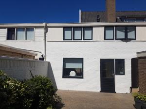滨海卡特韦克Vakantiehuis Katwijk Andreasplein的白色的房子,有黑色的门和窗户