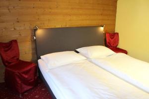 巴德哥依斯恩巨龙酒店的配有两张红色椅子的房间内的两张床