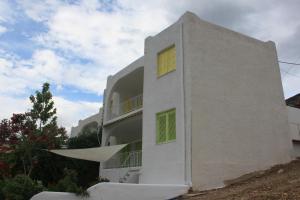 AlikíVillla Giallo的白色的建筑,上面有绿色百叶窗