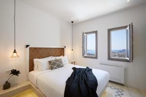 皮尔戈斯White & Co. La Torre Suites的卧室配有一张白色大床和两个窗户