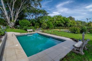 阿拉胡埃拉Villa Margarita的庭院旁带长凳的游泳池