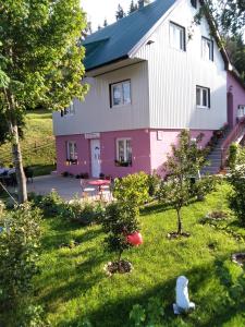 扎布利亚克Apartments Obradović Milan的一座粉色白色的房子,院子里有树木
