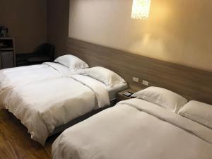 恒春古城河堤时尚旅店的酒店客房,配有两张带白色床单的床