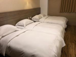 恒春古城河堤时尚旅店的配有白色床单和枕头的三张床