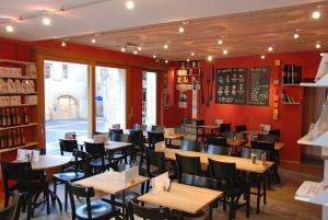 纳沙泰尔Le Café-Hôtel de L'Aubier的餐厅设有木桌和椅子,拥有红色的墙壁