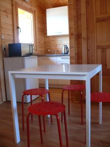 米耶伦科Anielsko domki nad morzem的厨房配有一张白色桌子和两张红色凳子