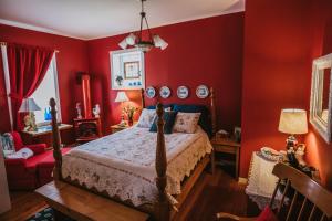ChepstowThe Chepstow Inn的卧室设有红色的墙壁、一张床和椅子