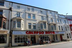 布莱克浦Calypso hotel Blackpool的一座白色的大建筑,前面的人在步行