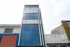 雅加达RedDoorz Plus @ Danau Sunter Utara的街道上一座高大的建筑,设有玻璃窗