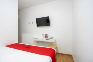 雅加达RedDoorz Plus @ Danau Sunter Utara的卧室配有一张床,墙上配有电视。