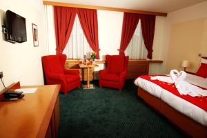 耶塞尼克Hotel Slovan的酒店客房,配有一张床和两张红色椅子