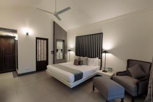 卡兰古特Andores Resort And Spa - Calangute的一间卧室配有一张床、一张沙发和一把椅子